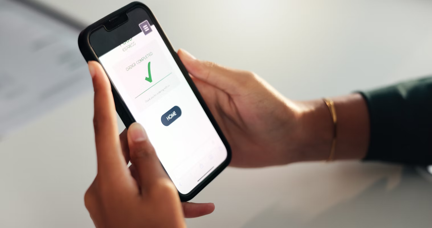 A user holding a phone displaying a green checkmark