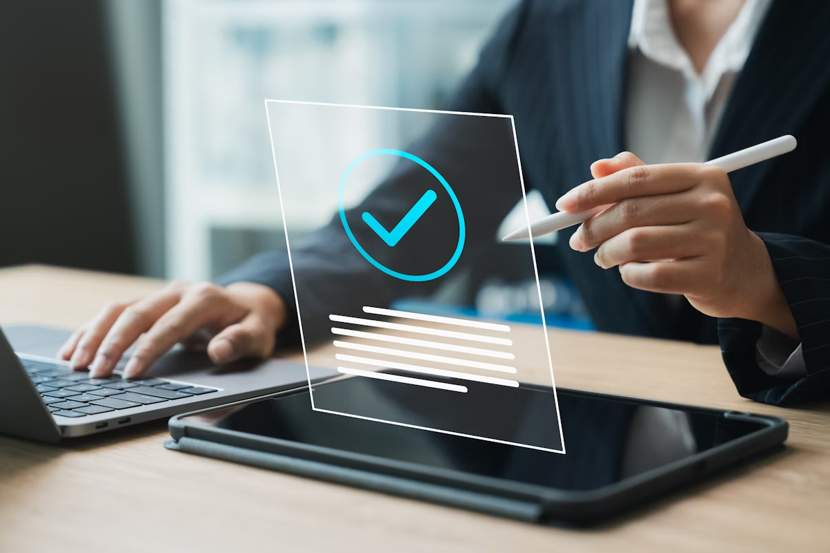 Person in business attire using a laptop and stylus. with a digital checkmark graphic.